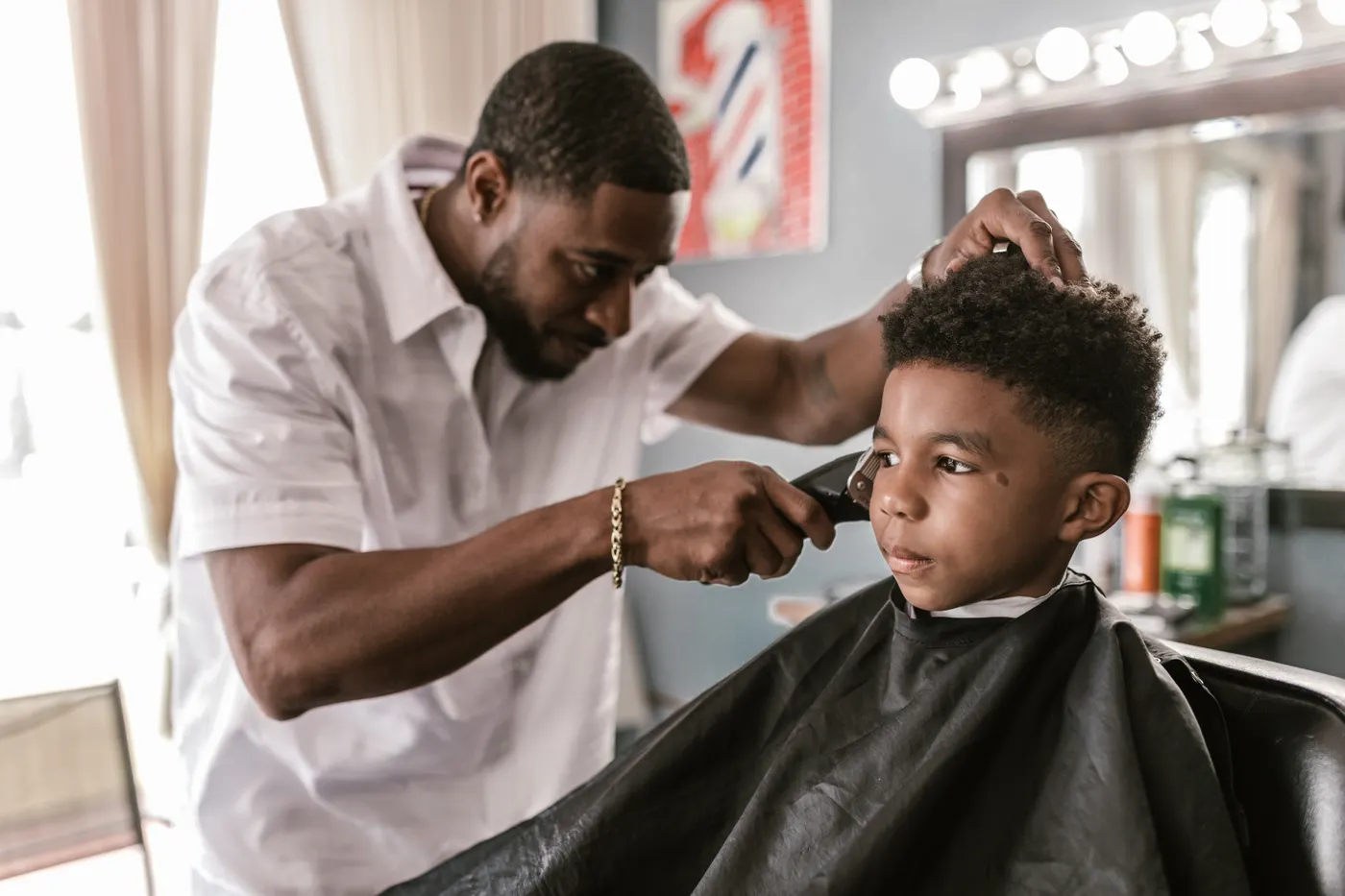 Coiffeur qui réalise un dégradé à la tondeuse sur un enfant